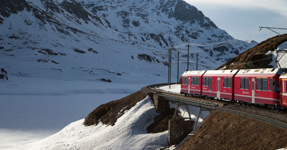Red Bernina Express train running through deep snow in the Swiss Alps